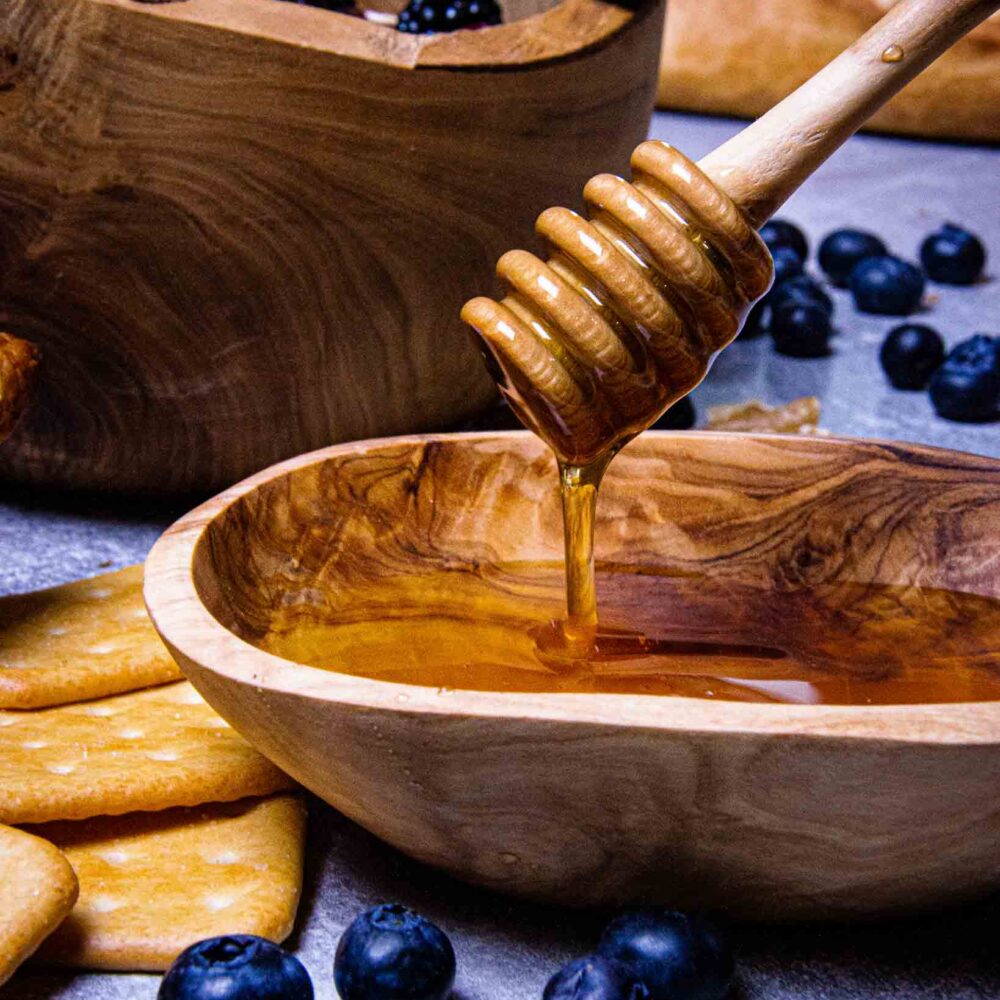 an-einem-hongloeffel-abfließender-honig