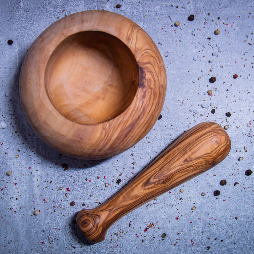 mörser-mit-stößel-aus-olivenholz-auf-grauen-hintergrund