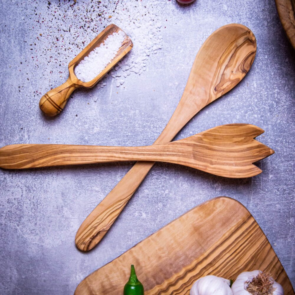 Salatbesteck aus Olivenholz auf grauem Hintergrund